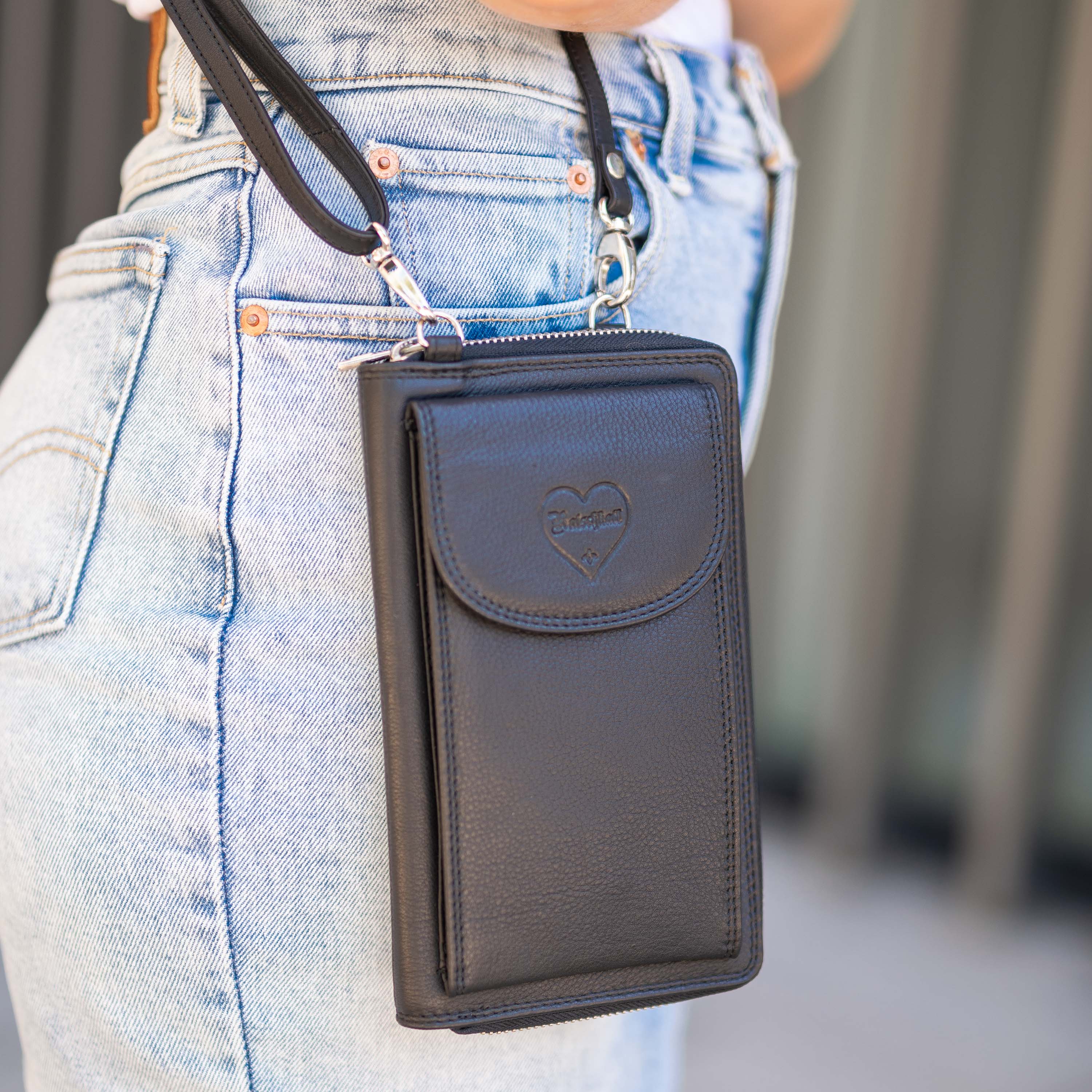 Schwarze Hodalump Leder-Handytasche mit Herzlogo, getragen an Jeanshose.