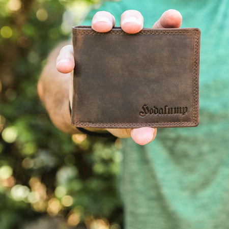 Mann hält braune Herren Geldbörse aus Leder von Hodalump im Vintage Stil.
