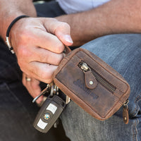 Mann hält braunes Hodalump Schlüsseletui aus Leder mit Autoschlüssel in der Hand.