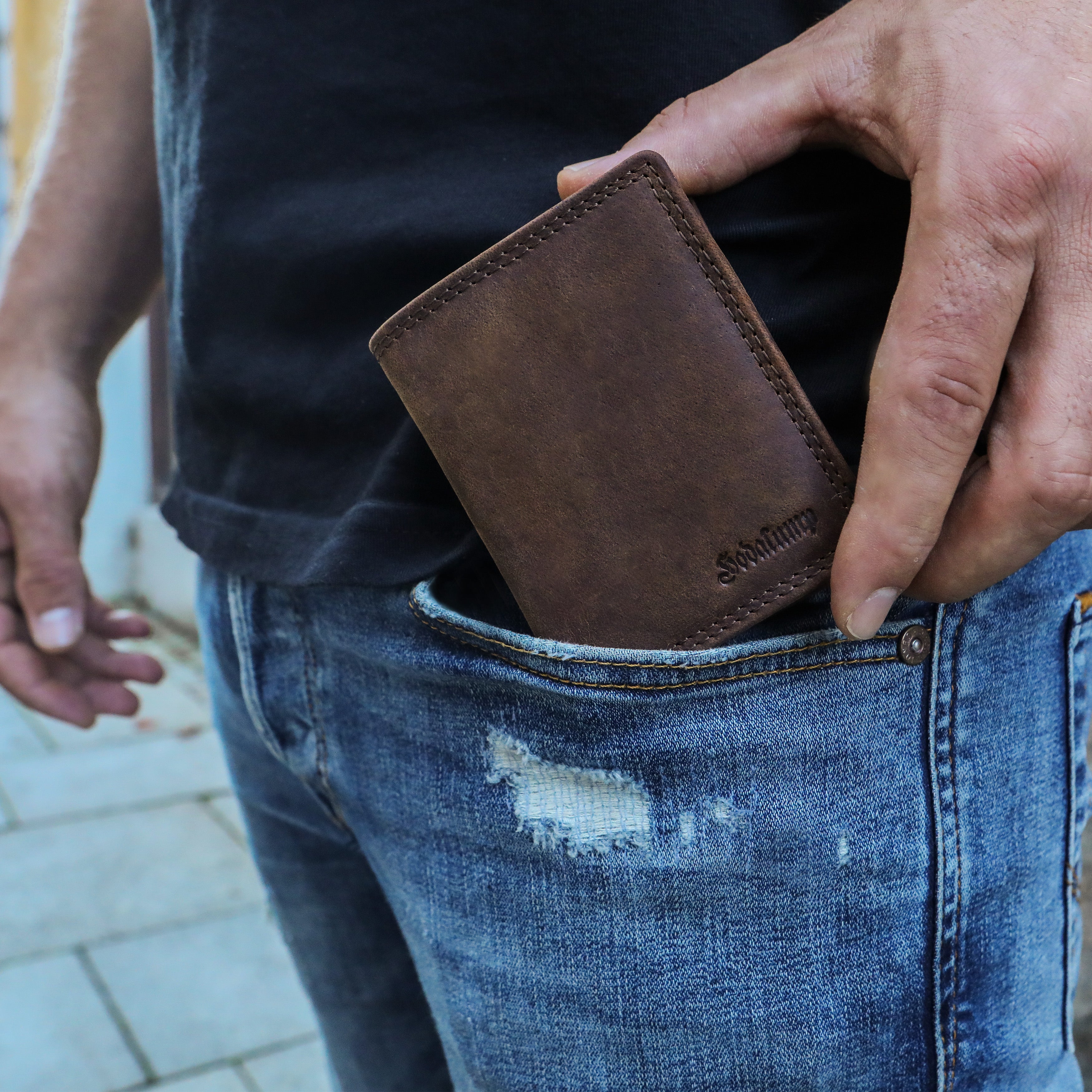 Mann steckt ein Slim Wallet Leder in die Hosentasche – schlankes Design für den Alltag