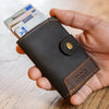 Person hält eine handgefertigte Slim Wallet Leder an einem Arbeitstisch – hochwertiges Handwerk aus echtem Leder