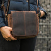 Person trägt braune Hodalump Umhängetasche aus Leder mit Klappe im Vintage Stil.