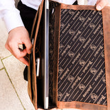 Mann steckt Laptop in braune Hodalump Laptoptasche mit bedrucktem Innenfutter.