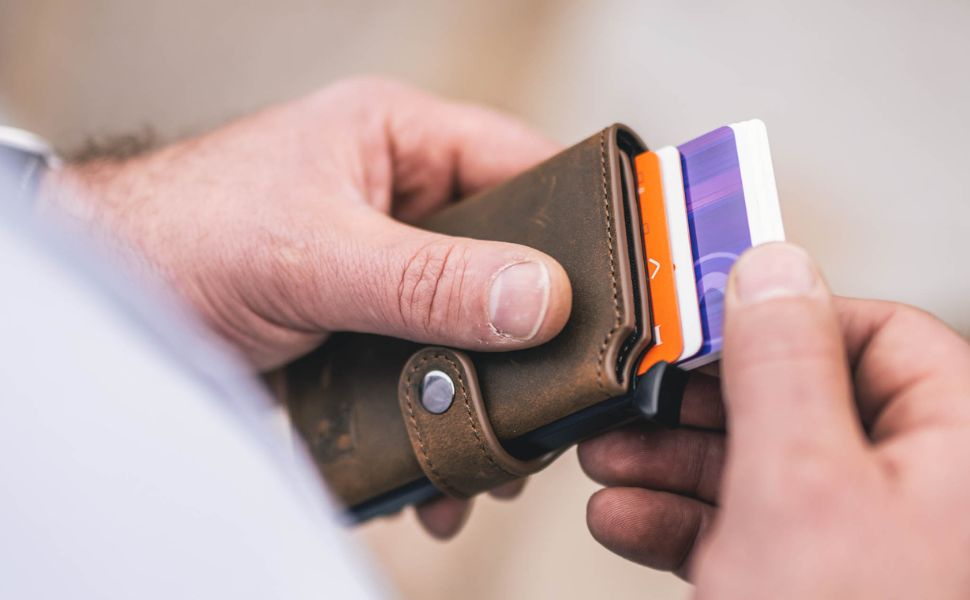 Person holt eine Karte aus einem Kartenetui aus Leder – hochwertiges und praktisches Kartenetui Leder im Einsatz.