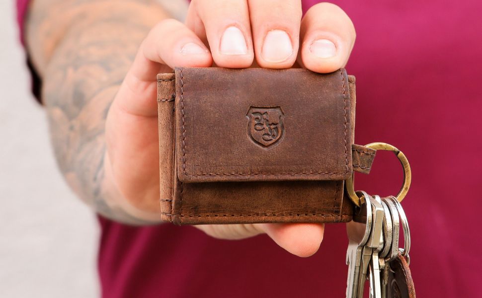 Person holt einen Schlüssel aus einem Schlüsseletui aus Leder – funktionales und elegantes Schlüsseletui Leder im Einsatz.